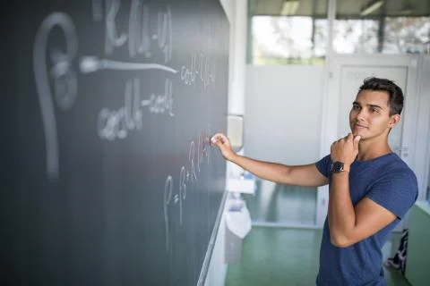 Handsome student solving a math problem on a blackboard Stock Photos