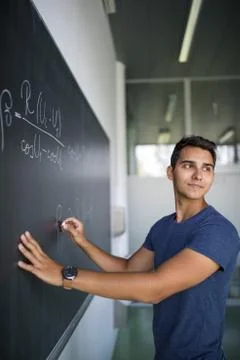 Handsome student solving a math problem on a blackboard Fotos de archivo