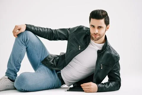 Handsome stylish man posing lying on floor over white studio background. Stock Photos