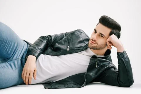 Handsome stylish man posing lying on floor over white studio background. Stock Photos