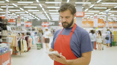 Handsome supermarket clerk using a touch screen tablet in supermarket Stock Footage 92236096