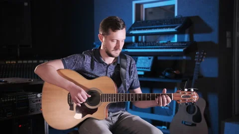 Handsome talented guy with a beard plays an acoustic guitar in a music studio Stock Footage 138266040