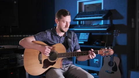Handsome talented guy with a beard plays an acoustic guitar in a music studio Stock Footage 138266135