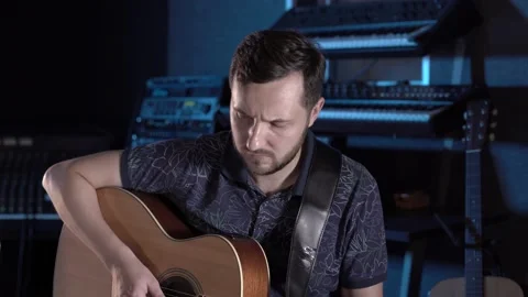 Handsome talented guy with a beard plays an acoustic guitar in a music studio Stock Footage 138463358