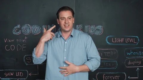 Handsome teacher teaching engineering code while standing at board. Edification Stock Footage 266946393