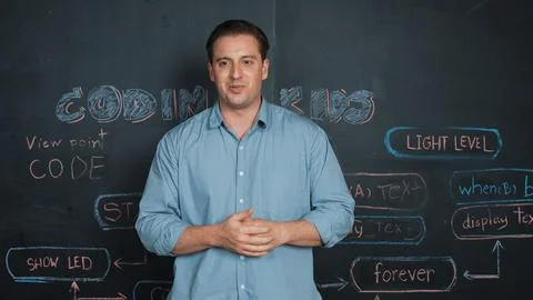Handsome teacher teaching engineering code while standing at board. Edification. Foto stock