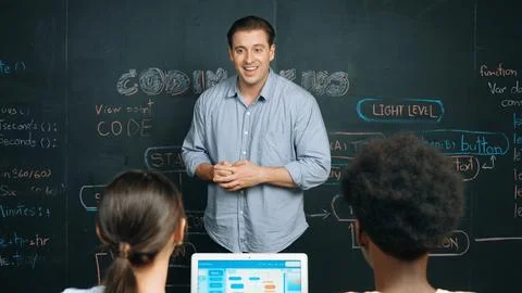 Handsome teacher teaching engineering code to diverse student. Edification. Stockfoto's