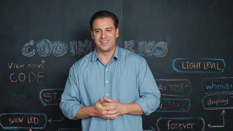 Handsome teacher teaching engineering code while standing at board. Edification. Foto stock