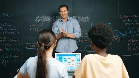 Handsome teacher teaching engineering code to diverse student. Edification. Stock Photos
