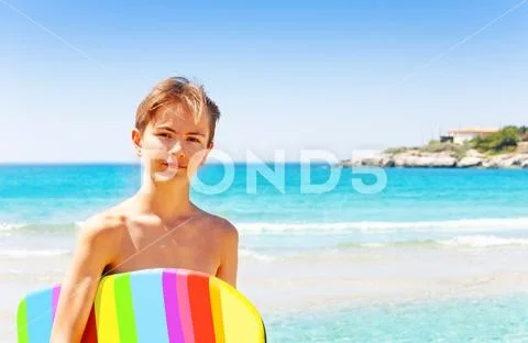 Handsome teenage boy with swim board on the beach Stock Photos