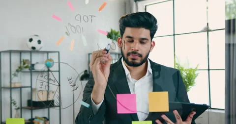 Handsome thoughtful skilled bearded guy in suit standing near glass wall in Stock Footage 157953489