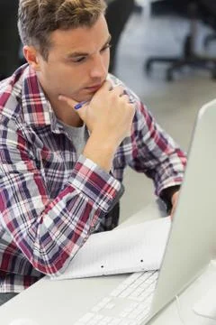 Handsome thoughtful student using computer taking notes 스톡 사진