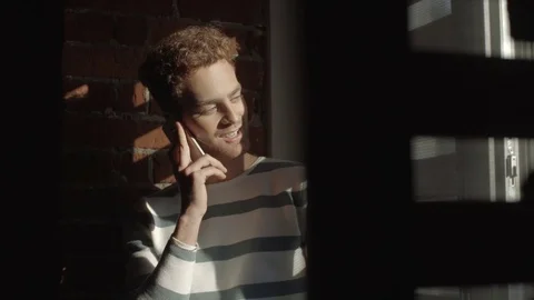 Handsome thoughtful young man talking on smart phone in modern loft interior. Stock Footage 70058991