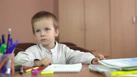 A handsome three year old boy sits at his desk in the class and thinks about the Stock-Footage 139201286