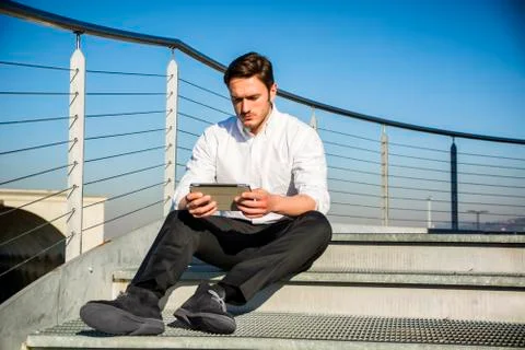 Handsome trendy man looking down at a tablet computer, outdoor Foto stock