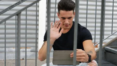 Handsome trendy man looking down at a tablet computer, outdoor Stock Photos