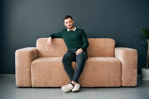 Handsome trendy man posing looking to camera while sitting on comfort sofa in Stock Photos