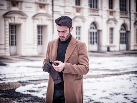 Handsome trendy man using cell phone in winter day Stock Photos