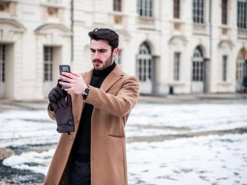 Handsome trendy man using cell phone in winter day Stock Photos