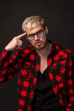 Handsome trendy young guy at the studio on black background. He wears beard and Stock-Fotos