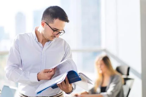 Handsome Turkish man is checking documents in a confident mood, there are def Foto stock