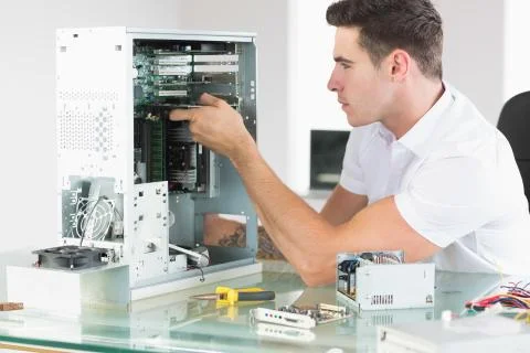 Handsome unsmiling computer engineer working at open computer Stock Photos