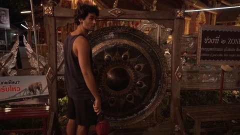 Handsome White Guy Hitting an Asian Gong / Bell in Chiang Mai Stock-Footage 124210895