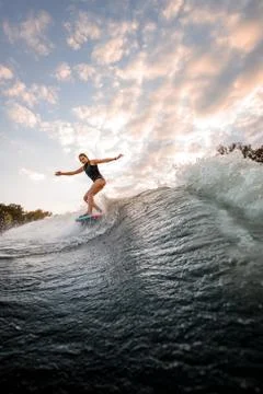 Handsome woman rides down on surf style wakeboard on splashed river wave Stock Photos