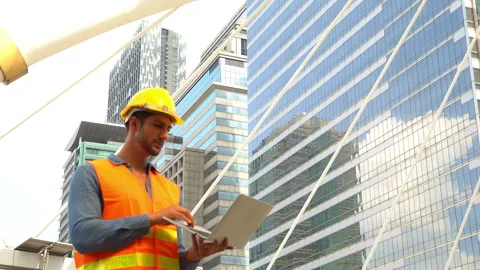 Handsome worker or engineer guy working on laptop and greeting his friend by Stock Footage 137444088