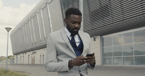 Handsome Young Afro American with Nice Smile Standing by the Building and Typing Stock Footage 124649646