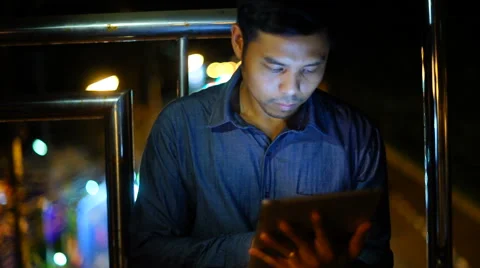 Handsome, young asain man with tablet computer in city at night Stock Footage 63580120
