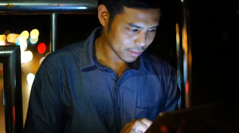 Handsome, young asain man with tablet computer in city at night Stock Footage 63580310