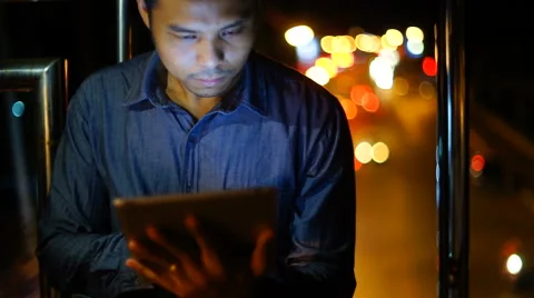 Handsome, young asain man with tablet computer in city at night Stock Footage 63587701