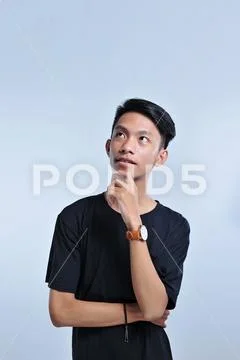Handsome young asian boy wearing black t-shirt and wristwatch with hand on ch Stock Photos