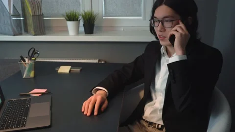 Handsome Young Asian Guy Working &amp; Talking on Phone at Office Smiling Stock Footage 148344079