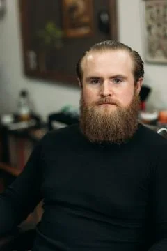 Handsome young bearded guy sitting in an armchair in a beauty salon Stock-Fotos