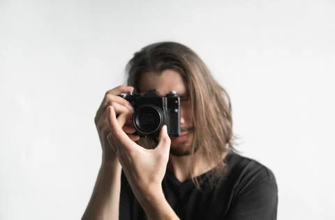 Handsome young bearded man with a long hair and in a black shirt holding vintage Stock Photos