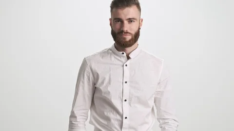 A handsome young bearded man is smiling isolated over white wall background Stock Footage 125320589