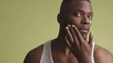 Handsome young black man applying facial cream with one hand. The concept of 스톡 동영상 233613445