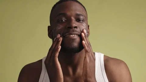 Handsome young black man applying facial cream and massaging it with both hands Stock-Footage 233613586