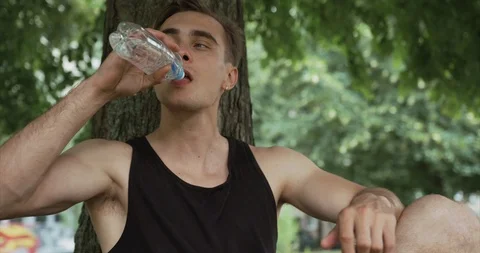 Handsome young blond man drinks water before warming up in the neighborhood. Stock Footage 95629114