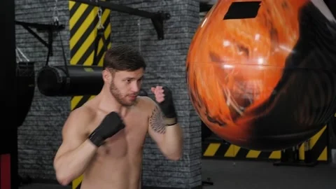 Handsome young boxer is exercising with a punching bag at the gym Stock Footage 150274383
