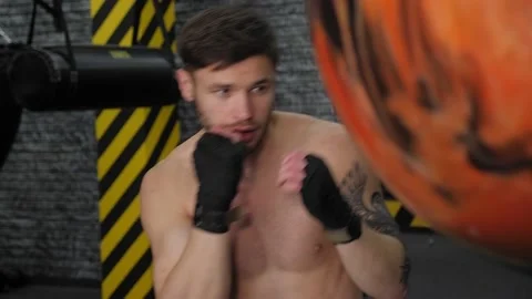 Handsome young boxer is exercising with a punching bag at the gym Stock Footage 150356764