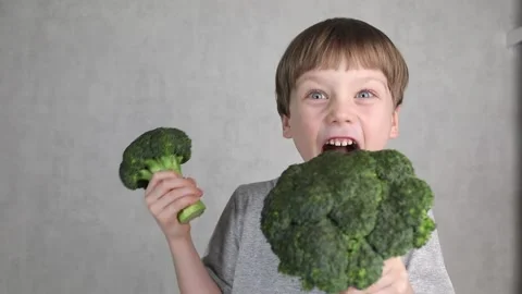 Handsome young boy holds fresh green broccoli in his hands. Stock Footage 236449614