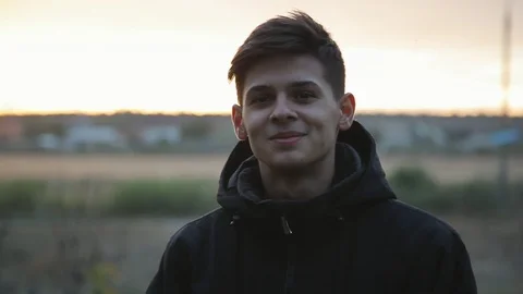 Handsome young boy standing at sunset outdoors Видео 97537587
