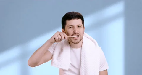 Handsome young brunette brushing teeth in bathroom with bamboo brush. Man Stock Footage 235900023