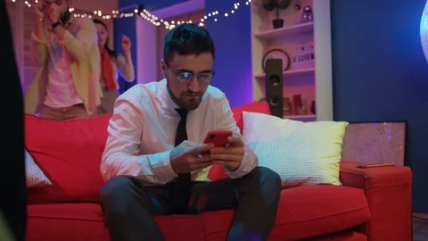 Handsome young businessman in glasses using mobile phone on sofa staying at home Stock Footage 122111197