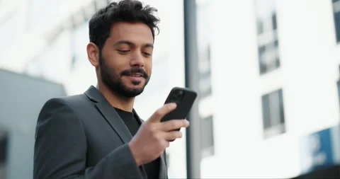 Handsome young businessman smiling while using a smartphone Stock Footage 244512204