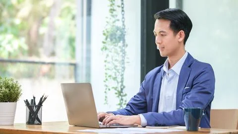Handsome young businessman using computer laptop while sitting in bright mo.. Stock Photos