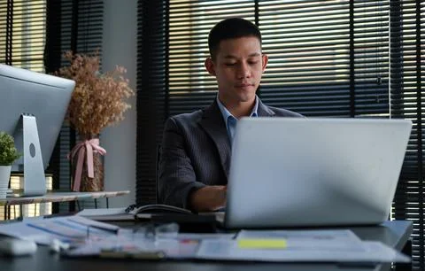 Handsome young businessman using computer laptop while sitting in bright mo.. Stock-Fotos